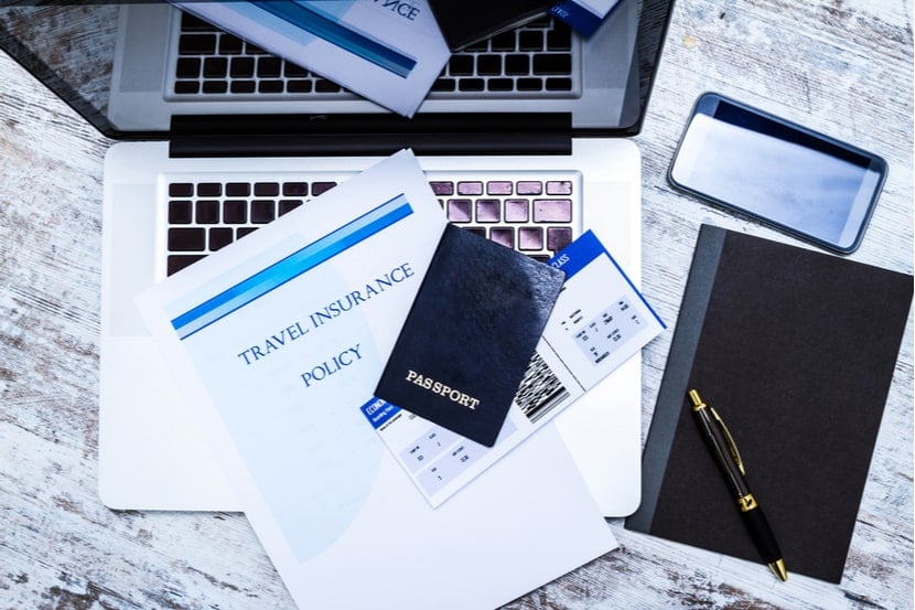 A travel insurance policy next to a laptop and phone 