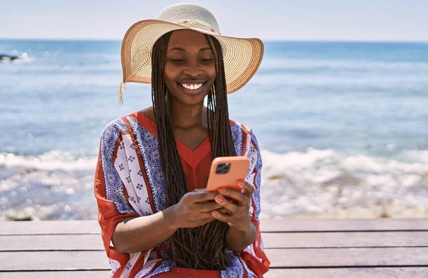 A woman holding a phone at the beach