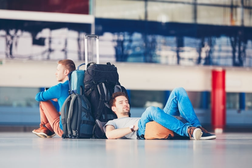 Two travellers sat fed up after a flight is delayed