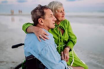 man in wheelchair looking out across beach 