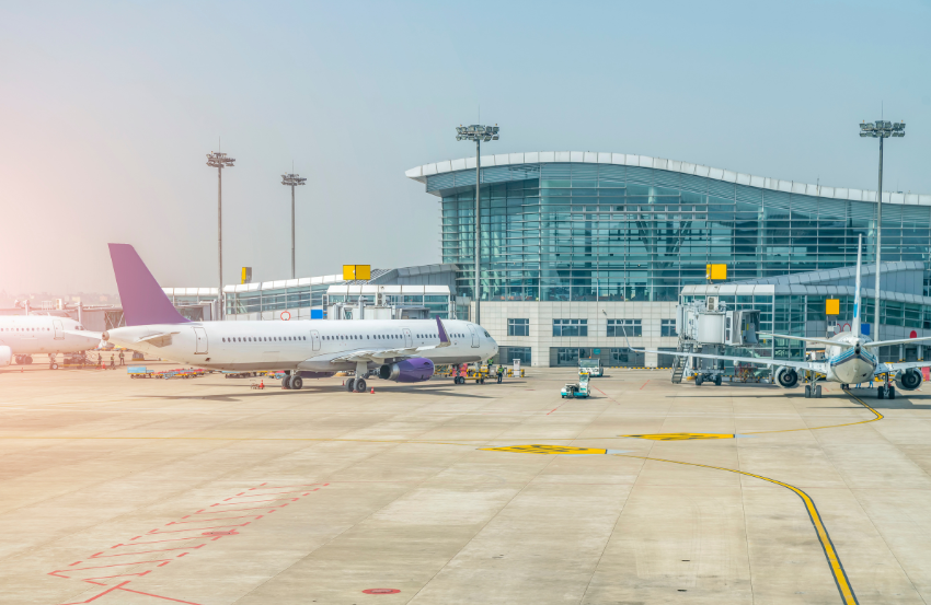 The outside of an airport terminal with a plane parked in front of it