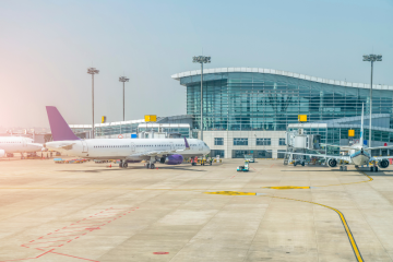 The outside of an airport terminal with a plane parked in front of it