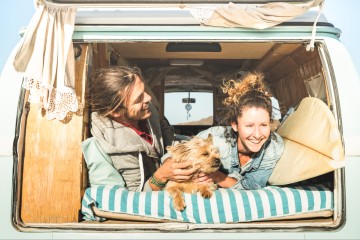 A couple and their dog looking out from their converted campervan