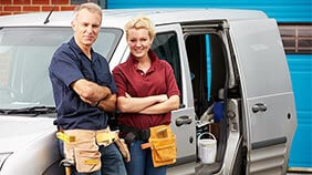 Tradespeople stood outside van with tools