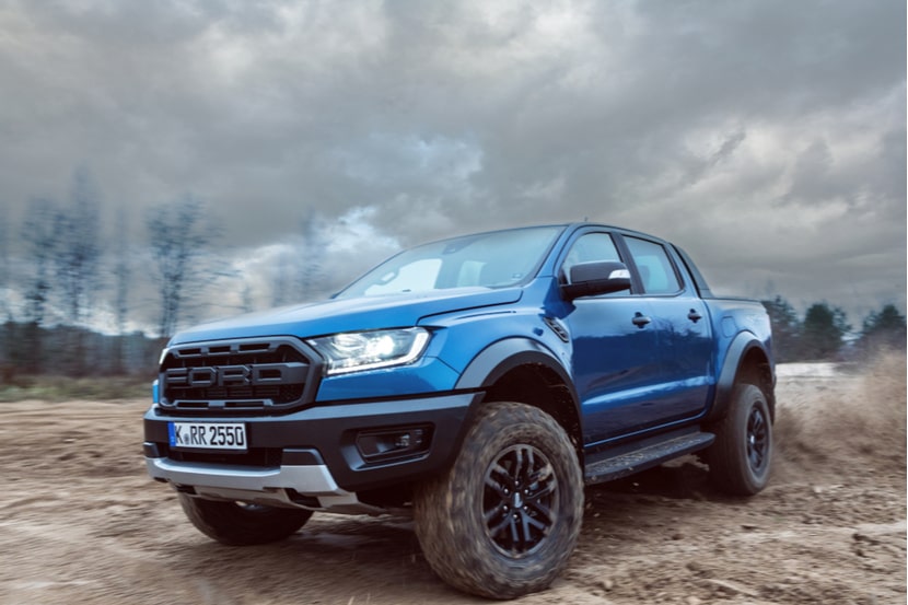A blue Ford Ranger Raptor driving in mud