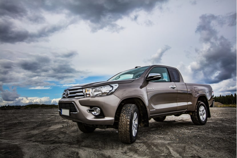 A grey Toyota Hilux parked in a mud field 