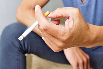 Close up of a hand holding a lit cigarette