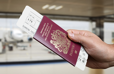 Hand holding a passport with a plane ticket inside