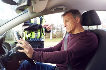 A person being pulled over at the side of the road by a police officer
