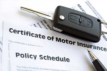 Car key on top of a certificate of motor insurance document