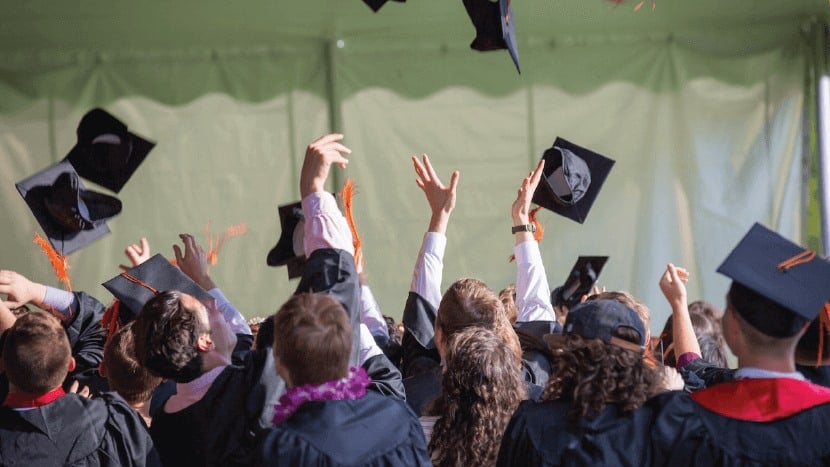 Studdents graduating and throwing their caps in the air